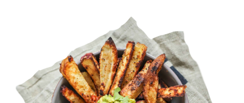 Roasted potato wedges with a green dip, served on a linen napkin.