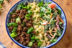 Blue-and-white bowl of spiced beef mince with spring onion, pale grainy rice substitute and creamy kaleslaw with tomato.
